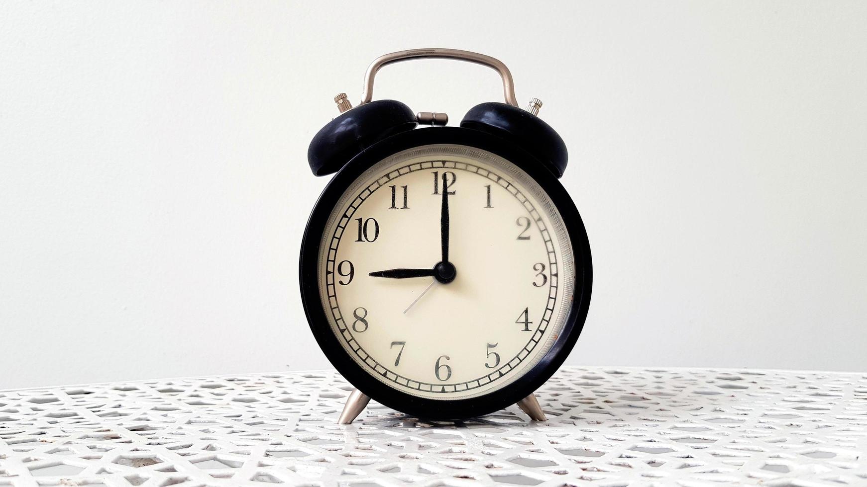 Vintage clock on table isolated on white background with copy space. Retro object. 9 o' clock. Morning time photo