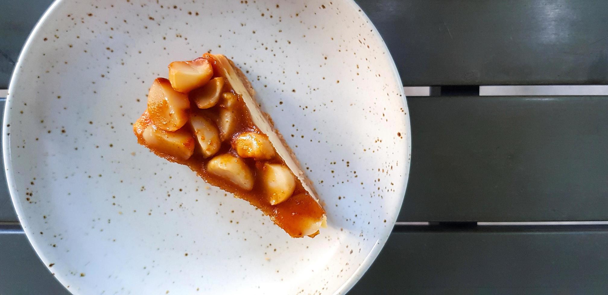 vista superior de una rebanada de tarta de queso macadamia en un plato blanco o plato con espacio para copiar a la derecha. endecha gorda de postre dulce y comida casera en la cafetería. foto