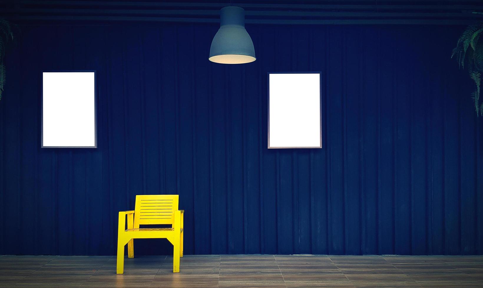 Yellow wooden chair with two picture frame or mockup and copy space for add wording or text on black shutter background in vintage tone. Dark wall and hanging light or lamp and vine, creeper plant. photo