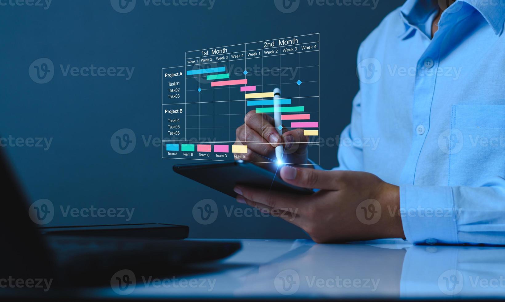 Project manager working on tablet and updating tasks and milestones progress planning with Gantt chart scheduling interface for company on virtual screen. Business Project Management System. photo