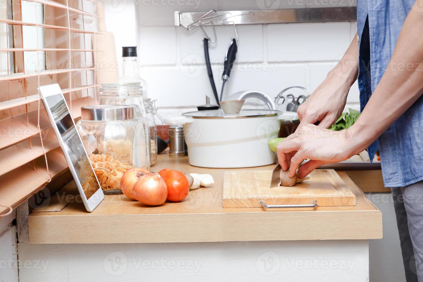 Asian men are happy to cook in the kitchen at home. Watching videos online learning through Tablet. Food concept. photo