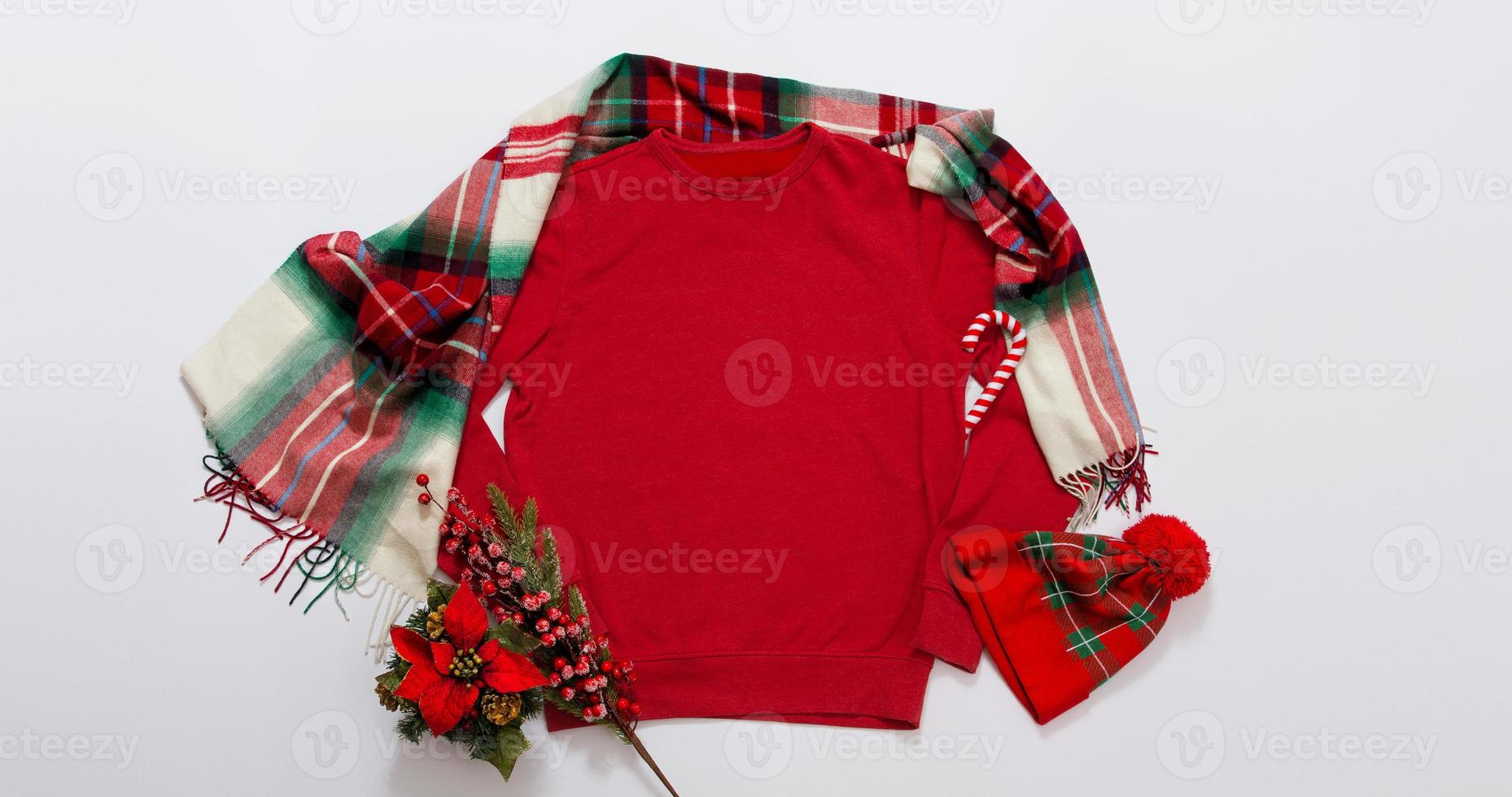 Close up banner red blank template sweatshirt with copy space and Christmas Holiday concept. Top view mockup hoodie and red holidays decorations on white background. Happy New Year accessories. Xmas photo