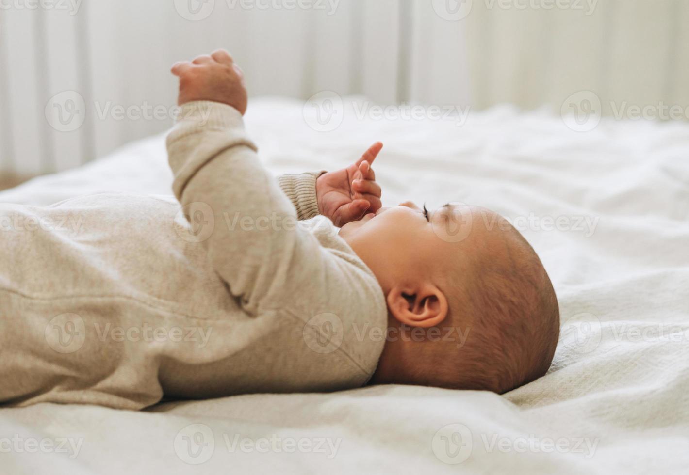 lindo bebé sonriente en general beige 5-6 meses en tonos naturales de cama foto