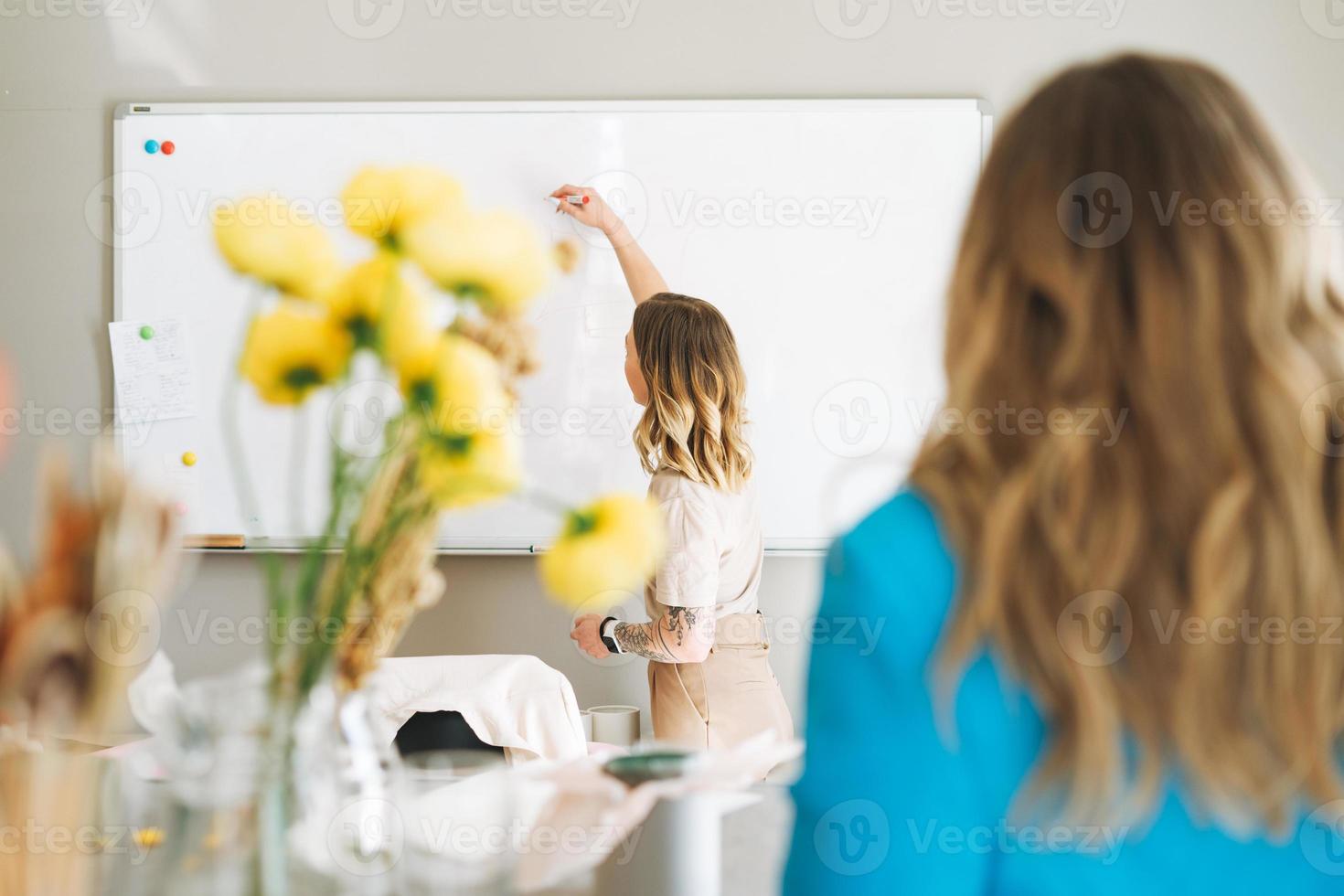 la joven rubia da una conferencia en un salón de clases. floristas escuchan clase sobre floristería moderna foto