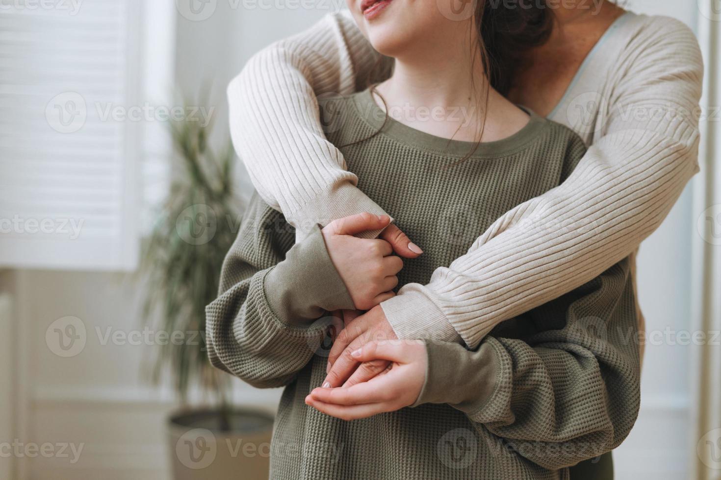 Crop portrait of mother middle age woman and daughter teenager together in the light interior photo