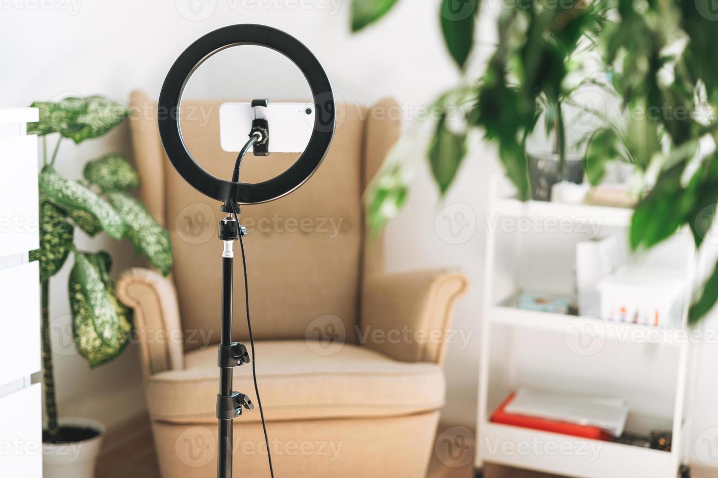 Mobile phone and ring lamp in cozy room at home or office. Equipment for blogging and recording video broadcasts and communicating with the social media photo