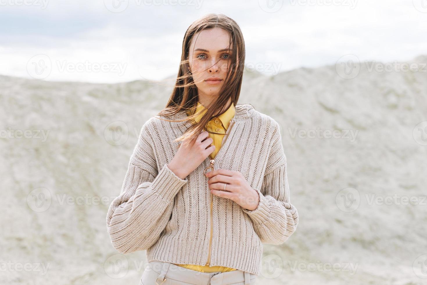 Fashion beauty portrait of young woman with long hair in knitted cardigan on the desert background, autumn outfit photo