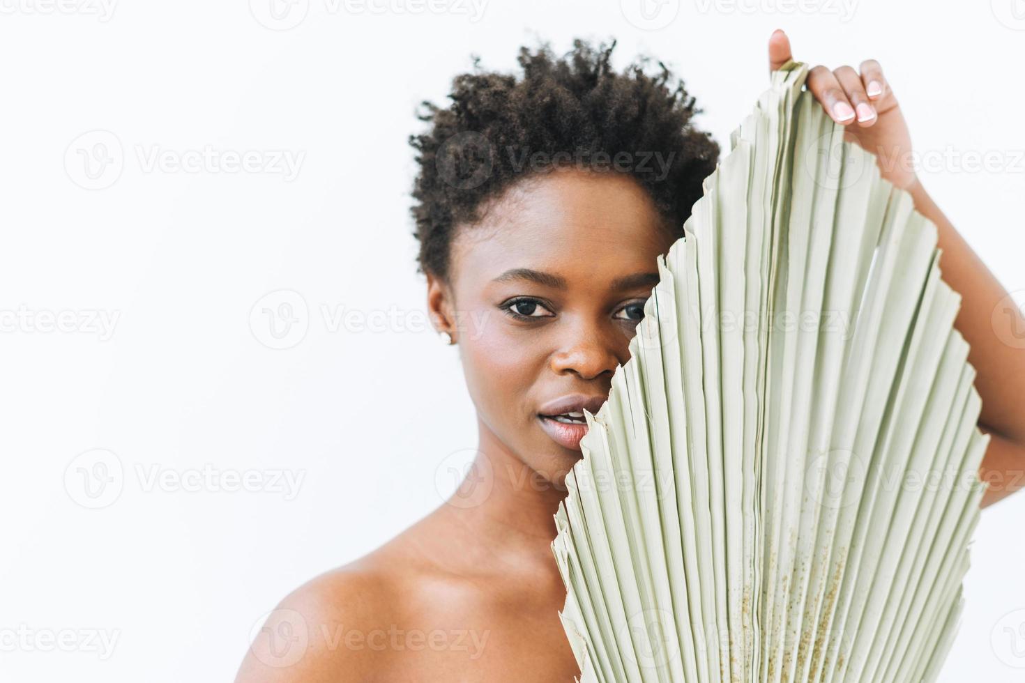bella sonriente joven afroamericana belleza modelo de moda con hoja seca sobre fondo blanco, concepto ecológico, belleza natural foto