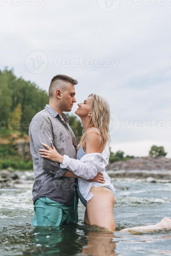 Happy young couple in love travelers kissing in the mountain river photo
