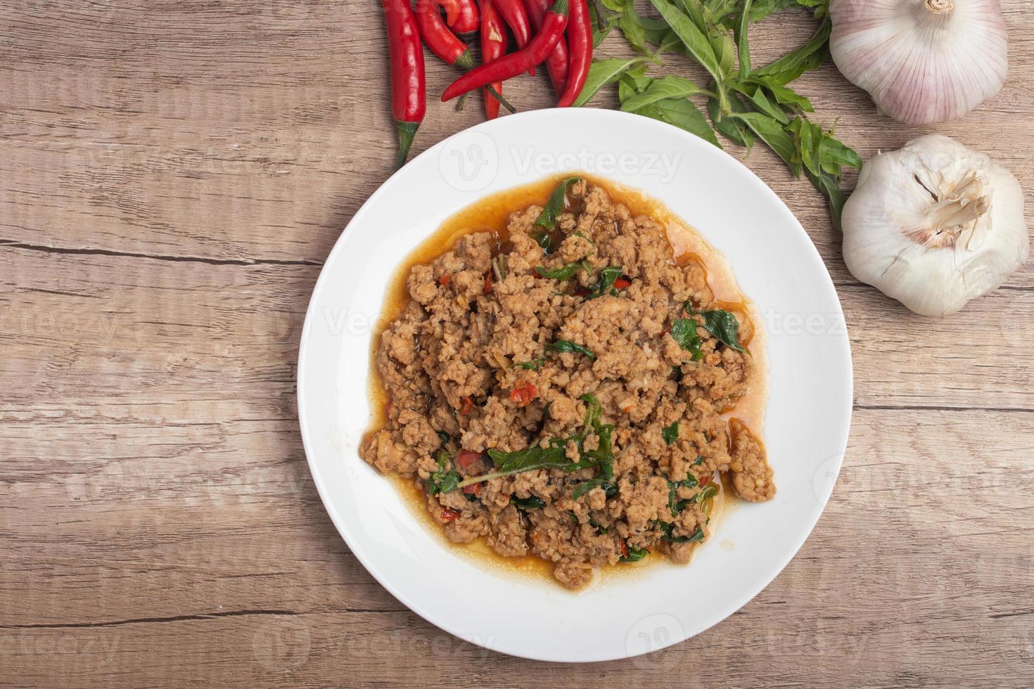 Pad kaprao, minced chicken in white plate on wooden background photo