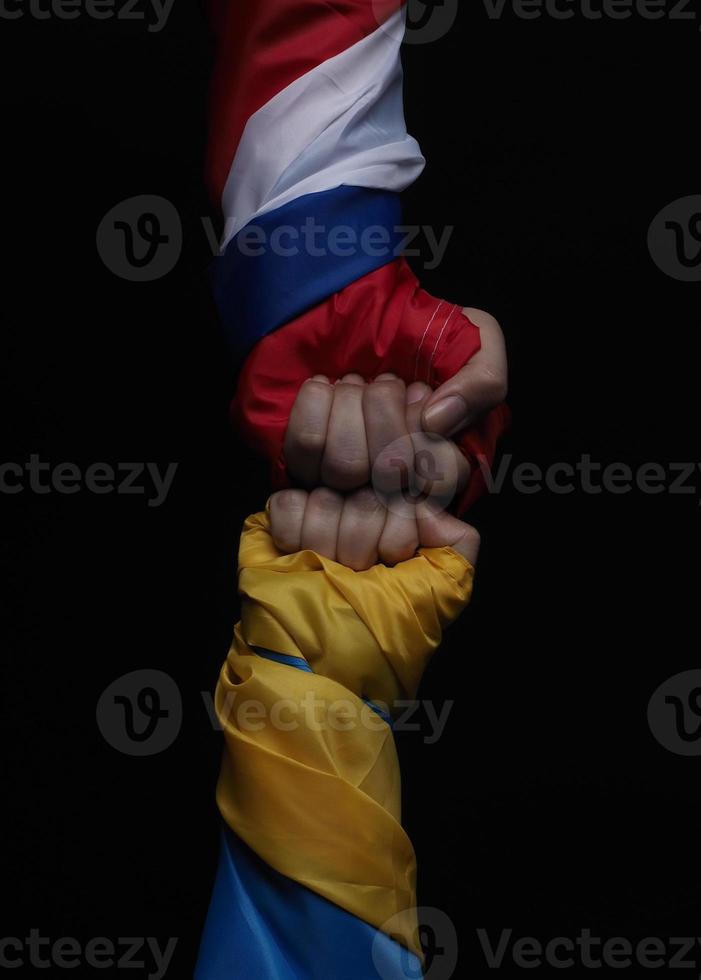 Russian flag and Ukraine flag in hands showing symbol of struggle war photo