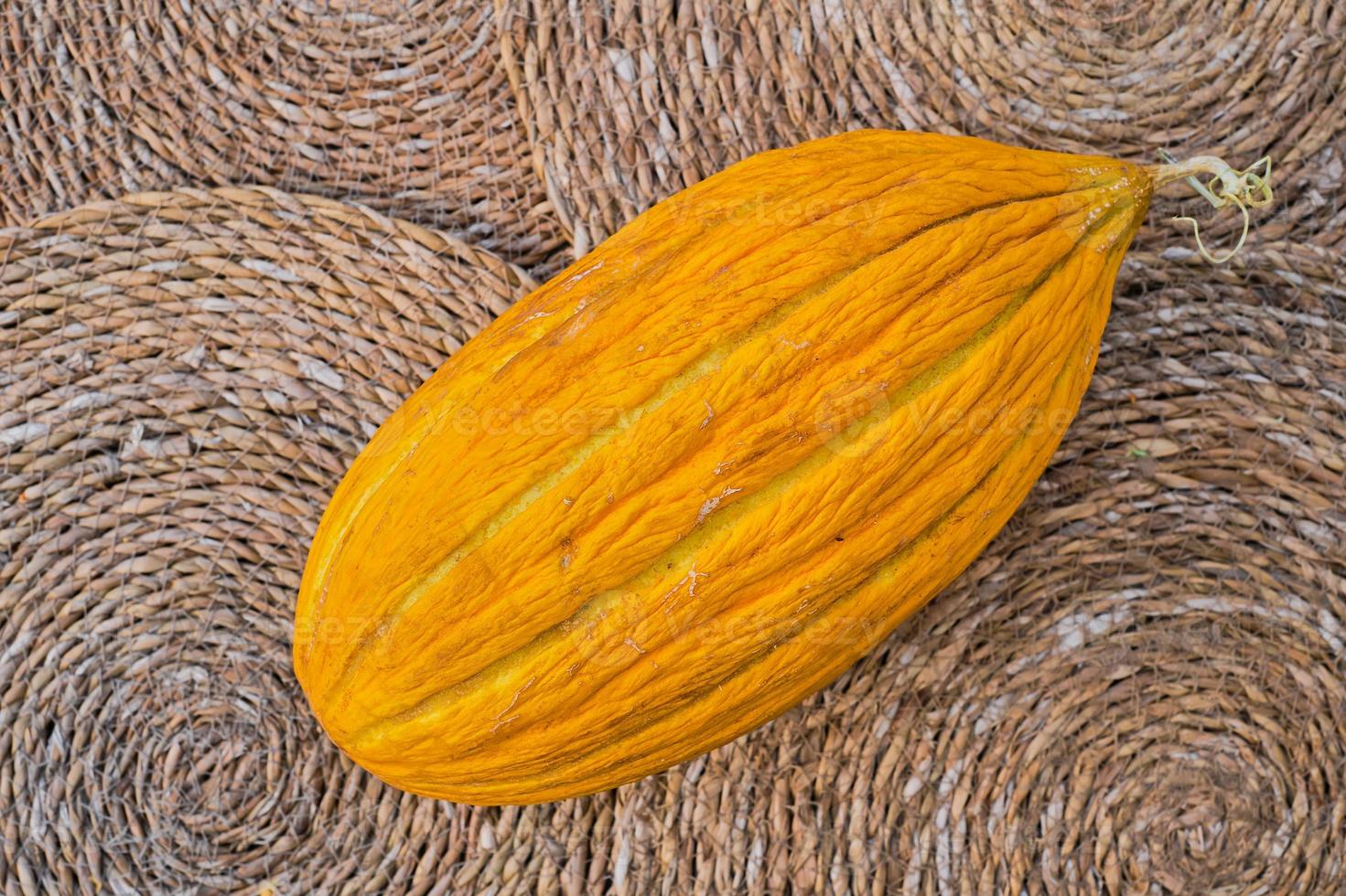 Ripe juicy yellow turkish melon on straw lined, top view, organic fruit advertising idea from farmers market. Concept for background or article photo