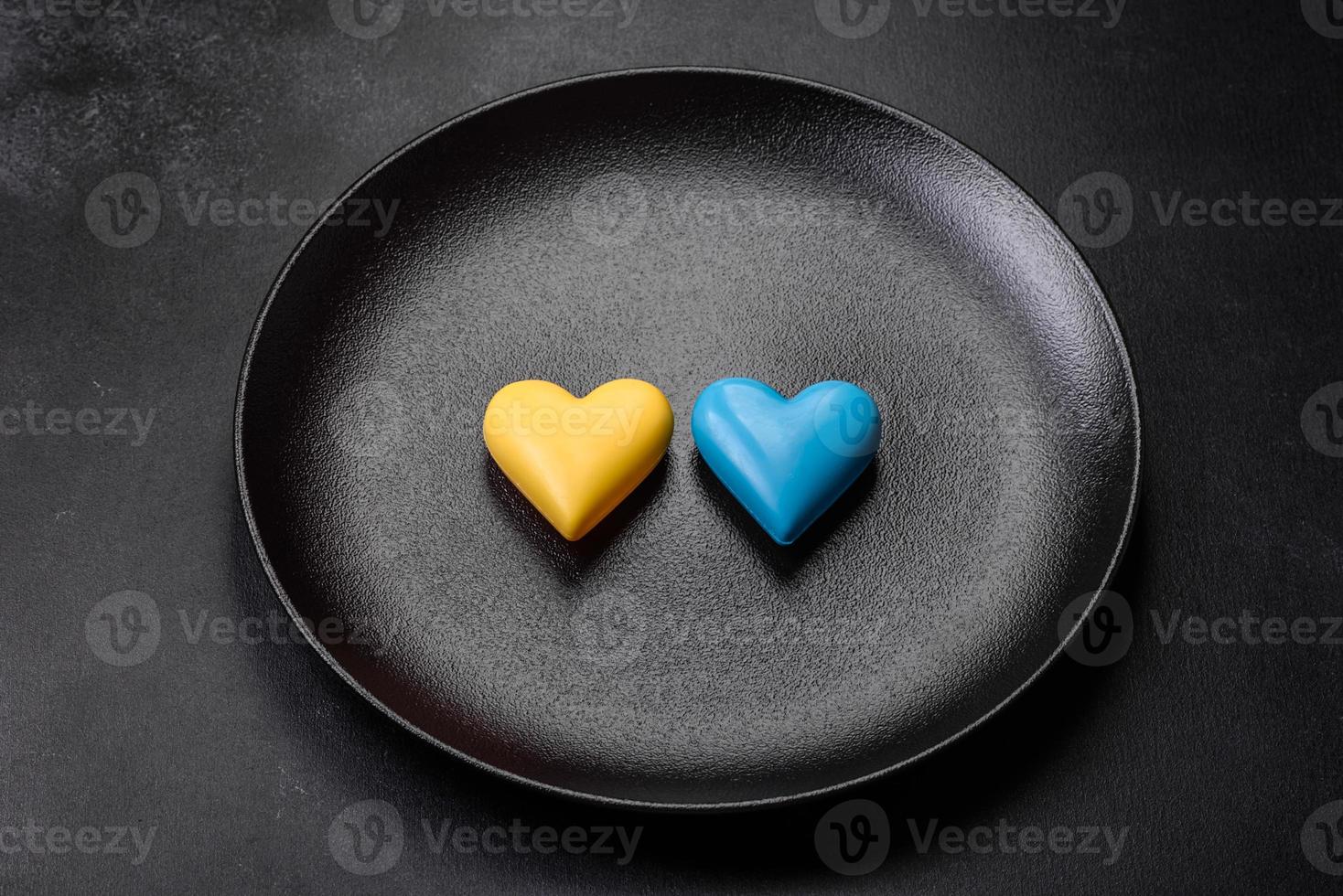 Chocolate hearts in the colors of the Ukrainian flag on a black ceramic plate photo