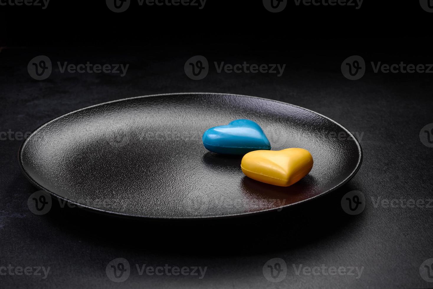 Chocolate hearts in the colors of the Ukrainian flag on a black ceramic plate photo