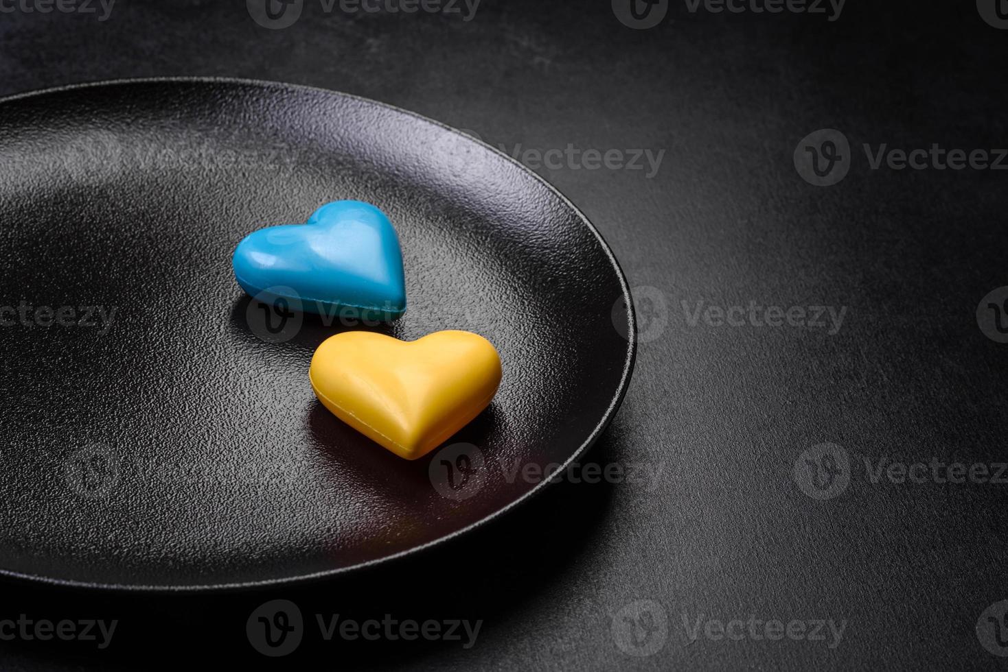 corazones de chocolate con los colores de la bandera ucraniana en un plato de cerámica negra foto