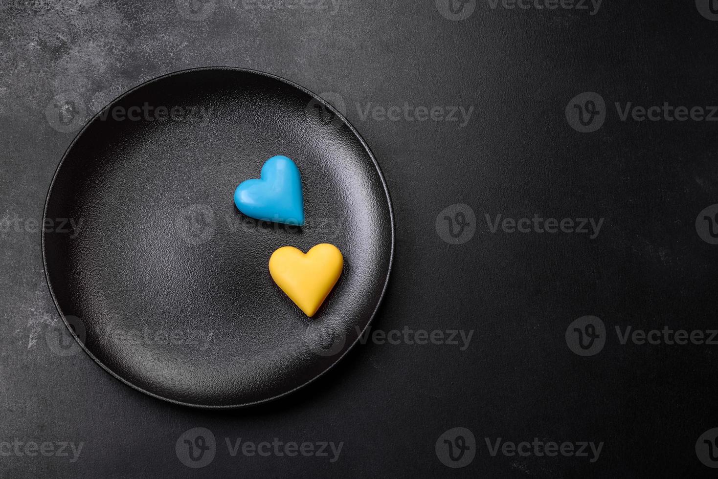 Chocolate hearts in the colors of the Ukrainian flag on a black ceramic plate photo