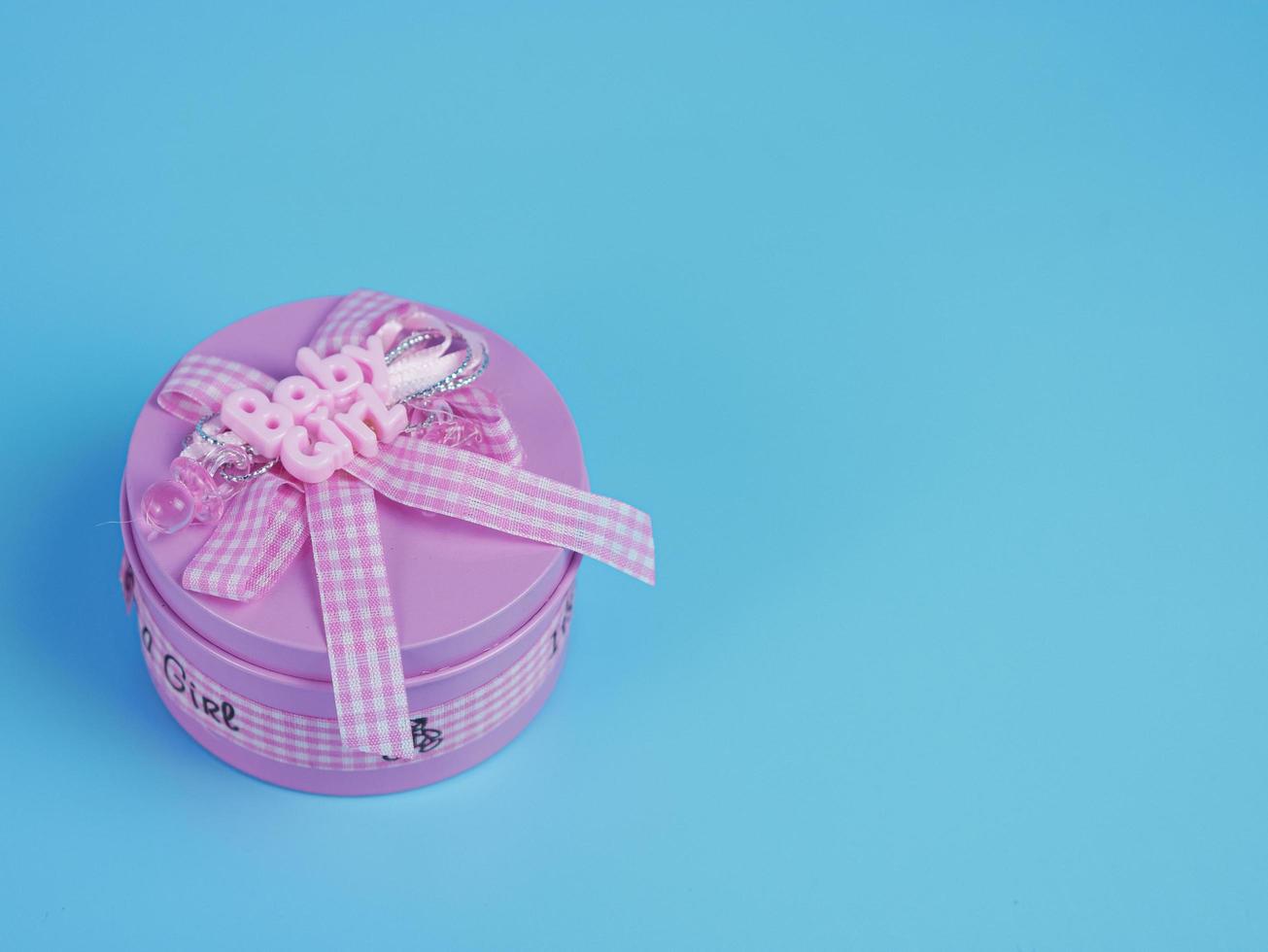 pink gift tin for baby girl isolated on blue background photo