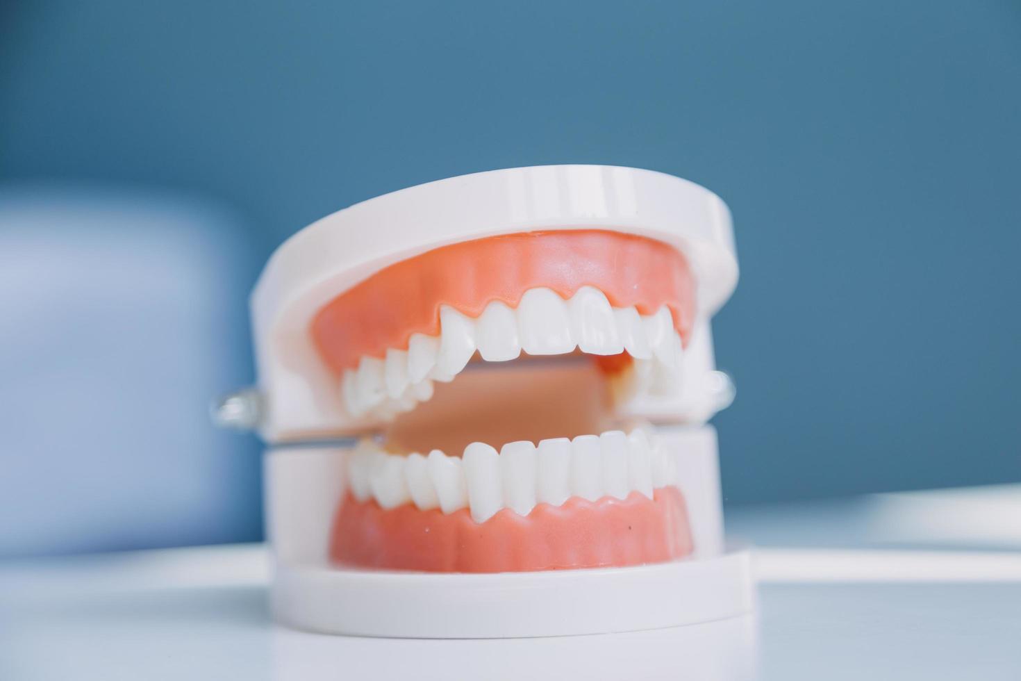 concepto de estomatología, retrato parcial de una chica con fuertes dientes blancos mirando la cámara y sonriendo, con los dedos cerca de la cara. primer plano, de, mujer joven, en, dentista, estudio, adentro foto