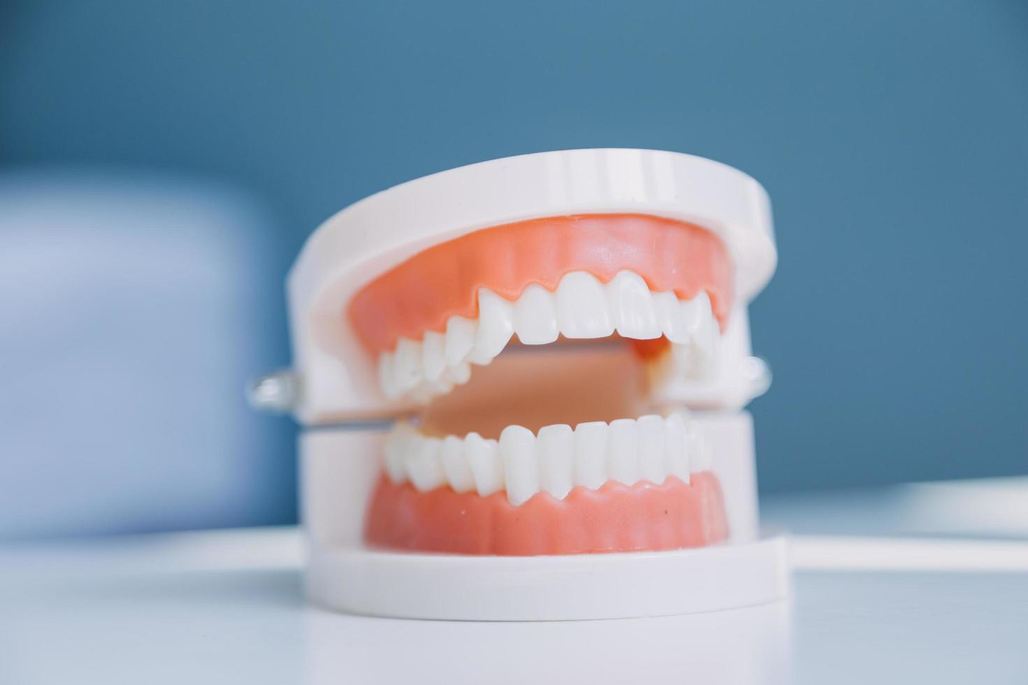 concepto de estomatología, retrato parcial de una chica con fuertes dientes blancos mirando la cámara y sonriendo, con los dedos cerca de la cara. primer plano, de, mujer joven, en, dentista, estudio, adentro foto