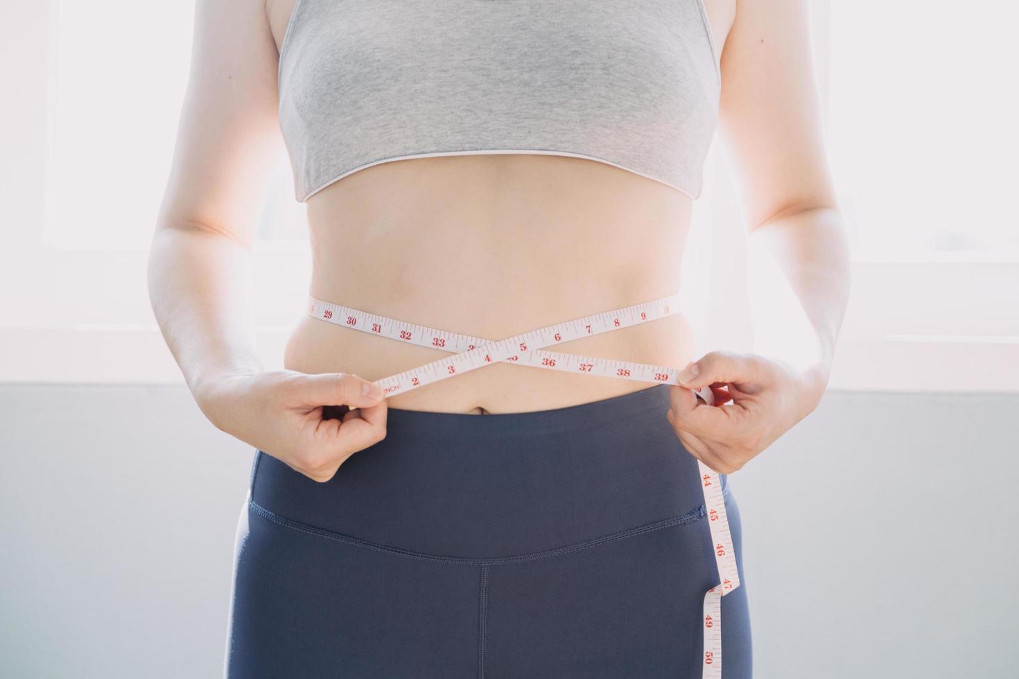 Beautiful fat woman with tape measure She uses her hand to squeeze the excess fat that is isolated on a white background. She wants to lose weight, the concept of surgery and break down fat under the photo