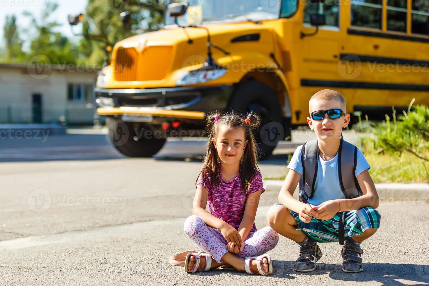 hermosa colegiala con compañeros de clase cerca del autobús escolar foto