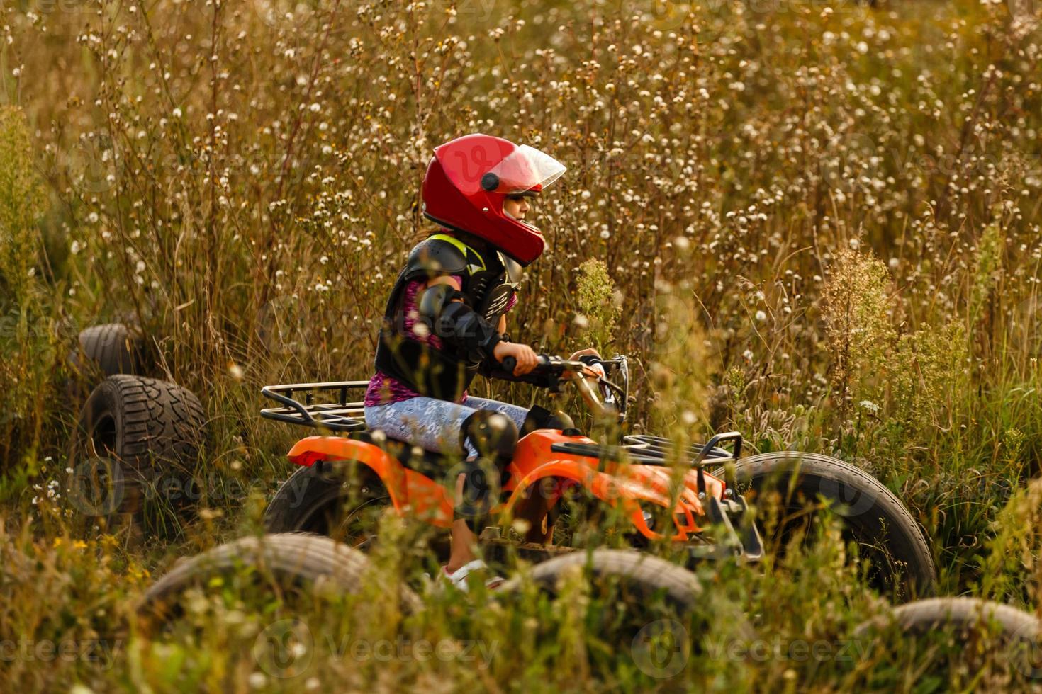 la niña monta un quad atv. una mini quad es una chica genial con casco y ropa protectora. El coche eléctrico de quad eléctrico para niños populariza la tecnología ecológica. foto