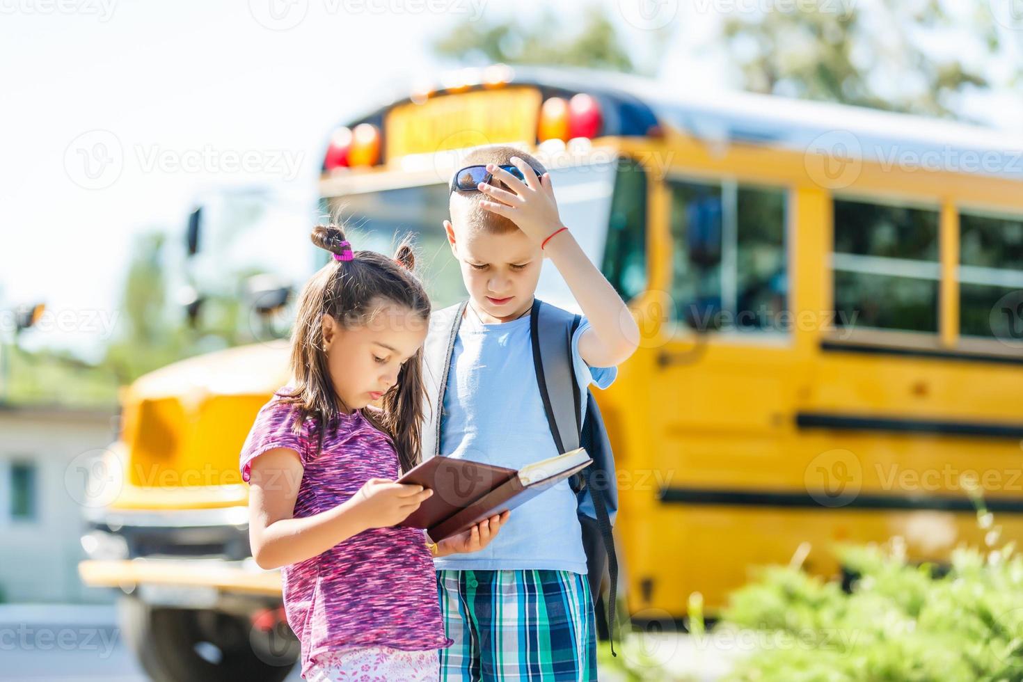 riendo sonriente niño caucásico estudiante niño con expresión de cara divertida caminando cerca del autobús amarillo el 1 de septiembre. educación y concepto de regreso a la escuela. niño alumno listo para aprender y estudiar. foto