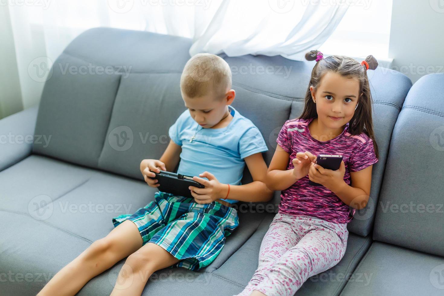 Cheerful children with smartphones in hands playing photo