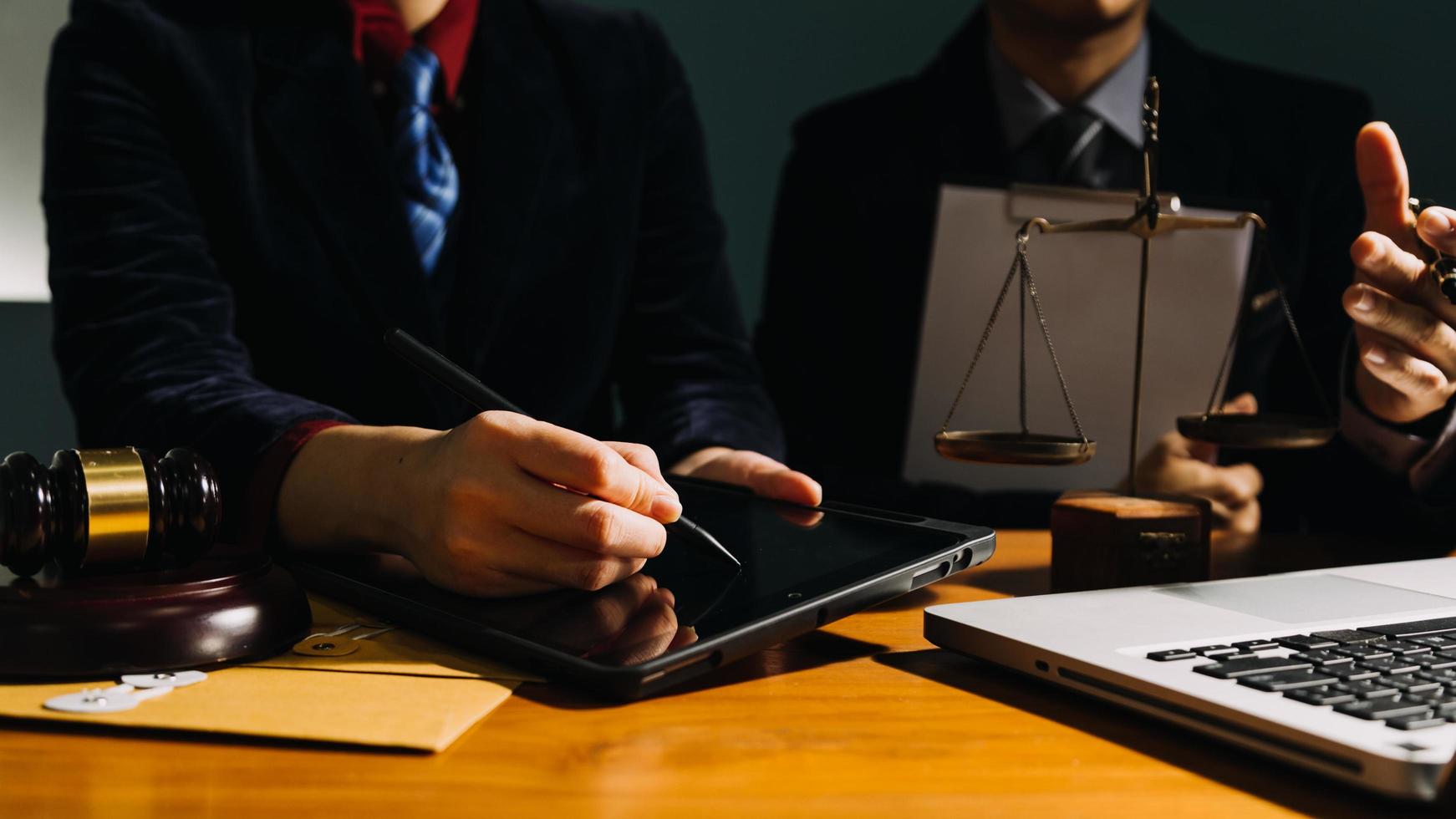 Business and lawyers discussing contract papers with brass scale on desk in office. Law, legal services, advice, justice and law concept picture with film grain effect photo