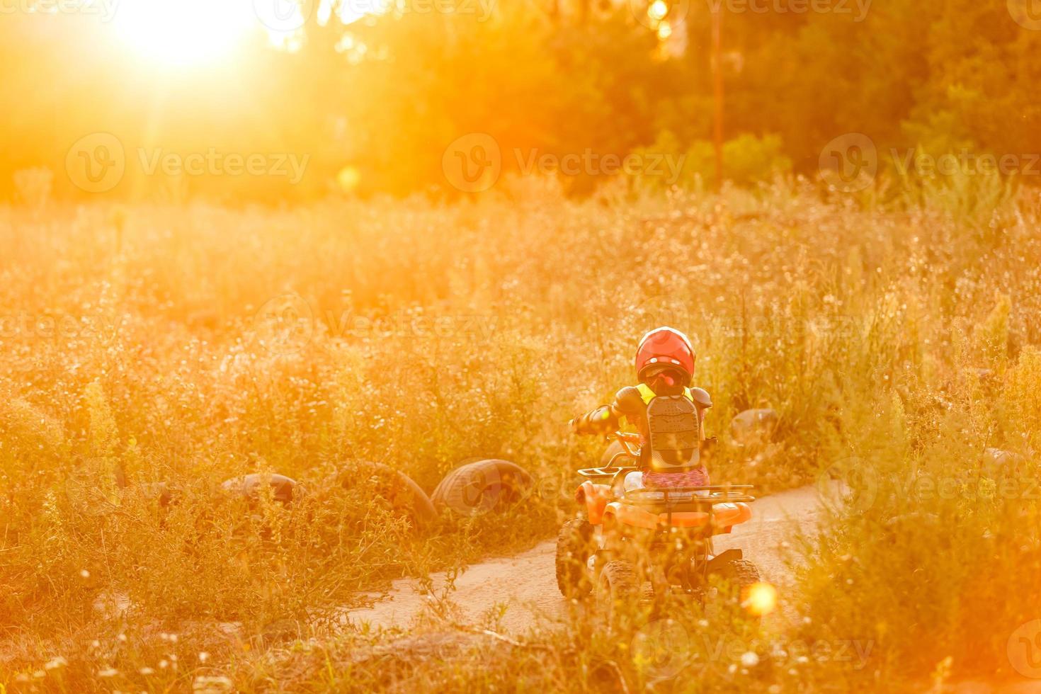 niña feliz jugando en la carretera durante el día. él conduce en quad en el parque. niño divirtiéndose en la naturaleza. concepto de felicidad. foto