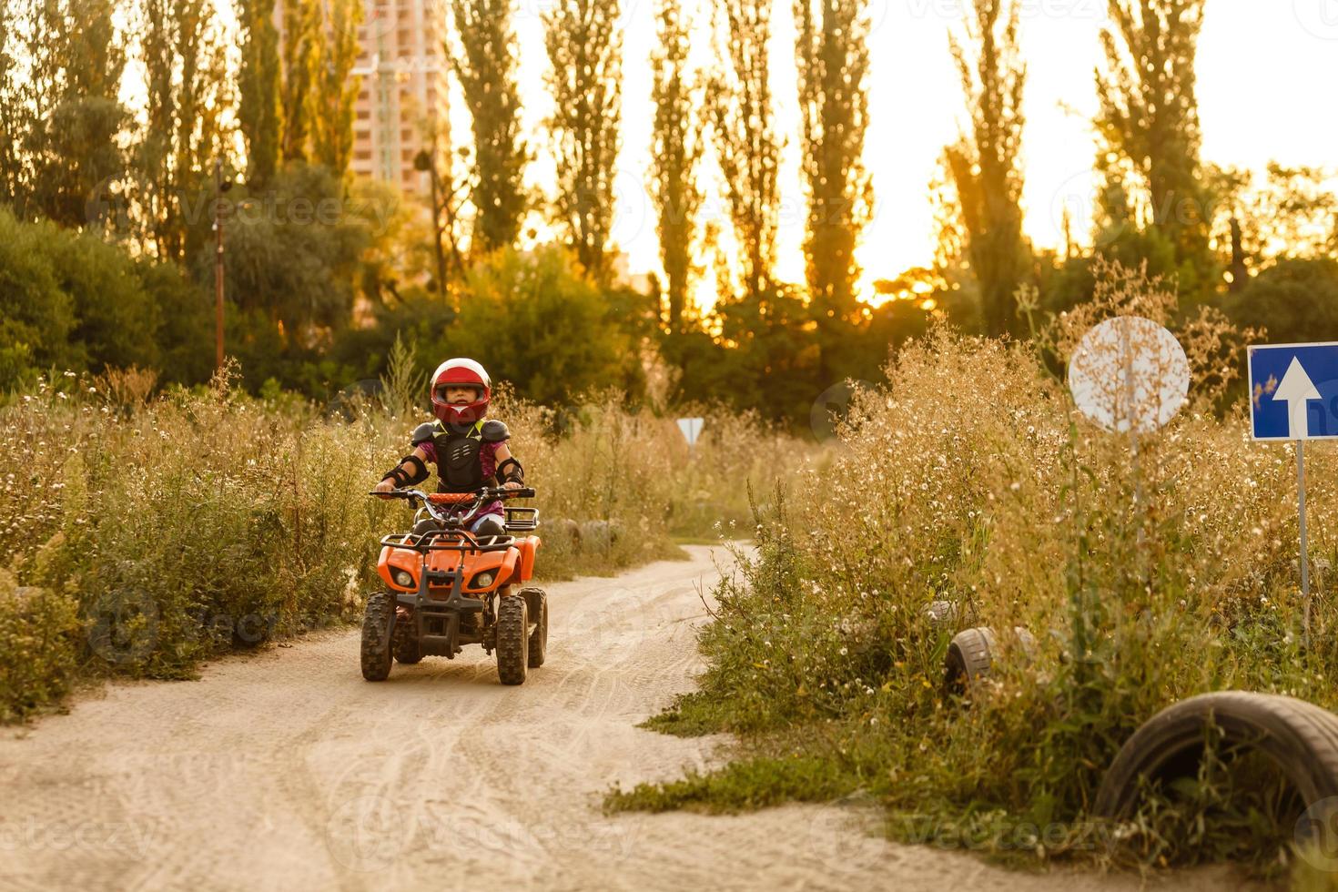 la niña monta un quad atv. una mini quad es una chica genial con casco y ropa protectora. El coche eléctrico de quad eléctrico para niños populariza la tecnología ecológica. foto