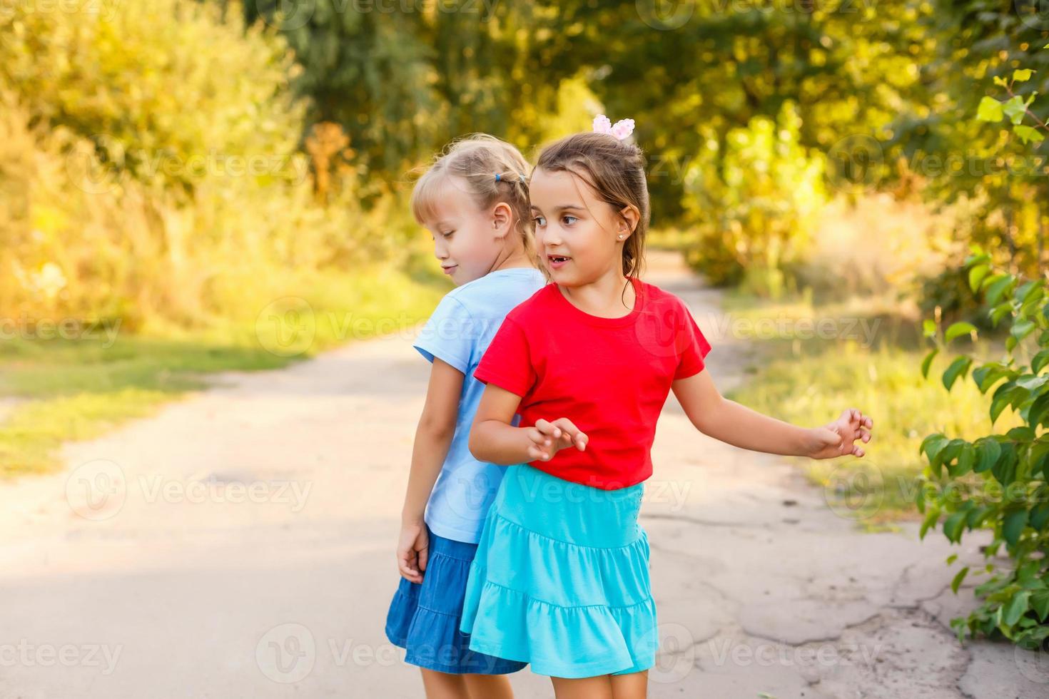 Back view of two little girls holding hand and walking together in the garden in vintage color tone photo