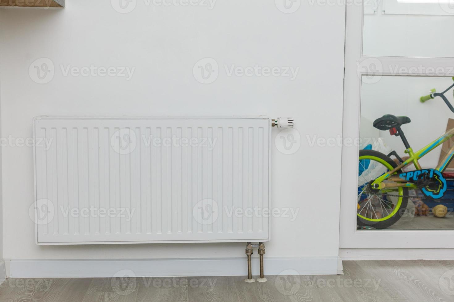 White heating radiator on wall in an apartment with wooden floo photo