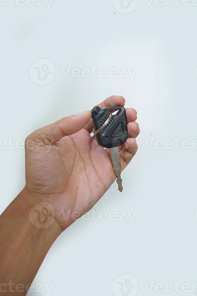 imagen de la mano del hombre asiático sosteniendo la llave de la motocicleta moderna aislada en el fondo blanco. foto