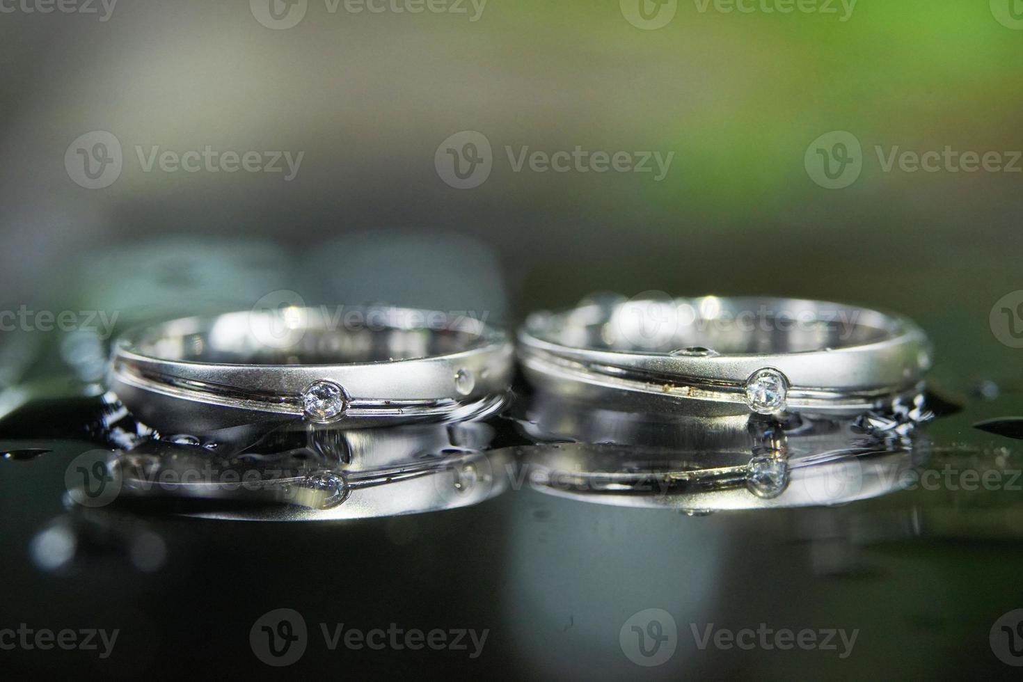 macrofotografía de un par de anillos de boda con reflejo debajo, de cerca foto