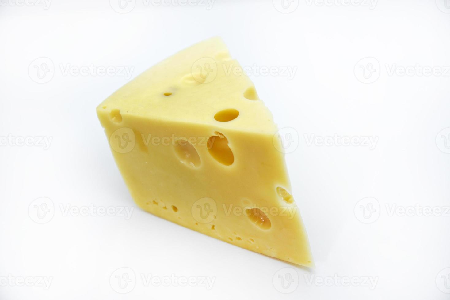 A large piece of cheese on a white background. A triangular piece of cheese with holes. photo
