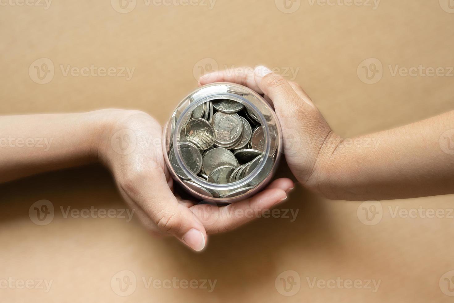 manos de niños sosteniendo monedas en un frasco juntas como concepto de ahorro para la familia o la educación. foto