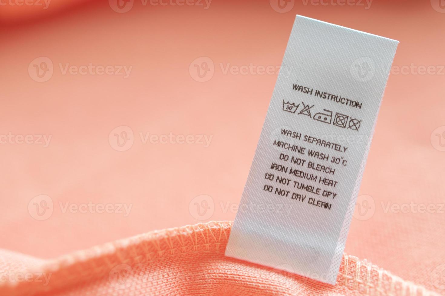 White laundry care washing instructions clothes label on pink cotton shirt photo