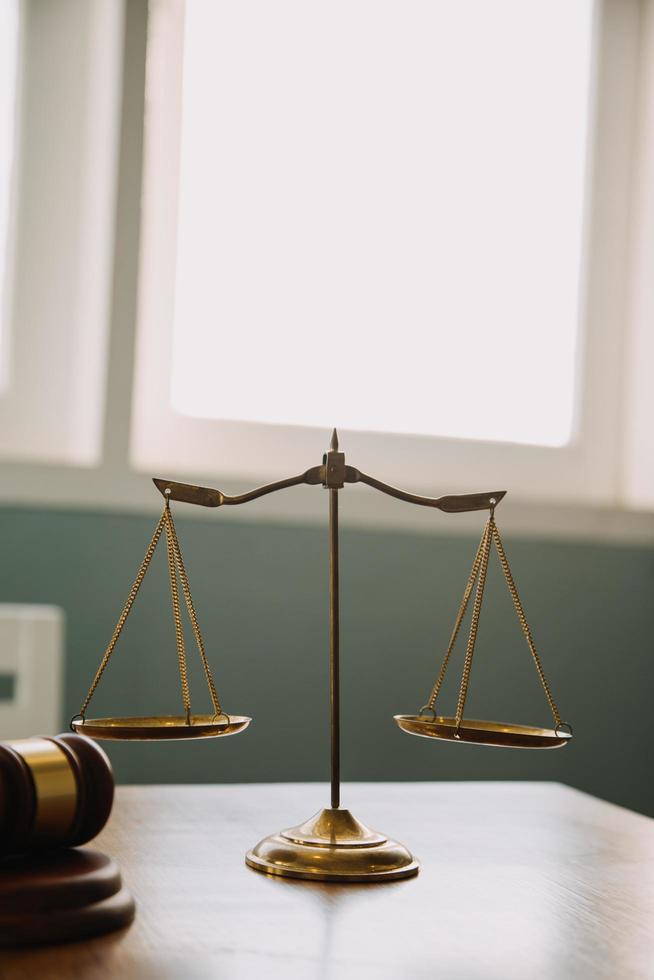 Business and lawyers discussing contract papers with brass scale on desk in office. Law, legal services, advice, justice and law concept picture with film grain effect photo