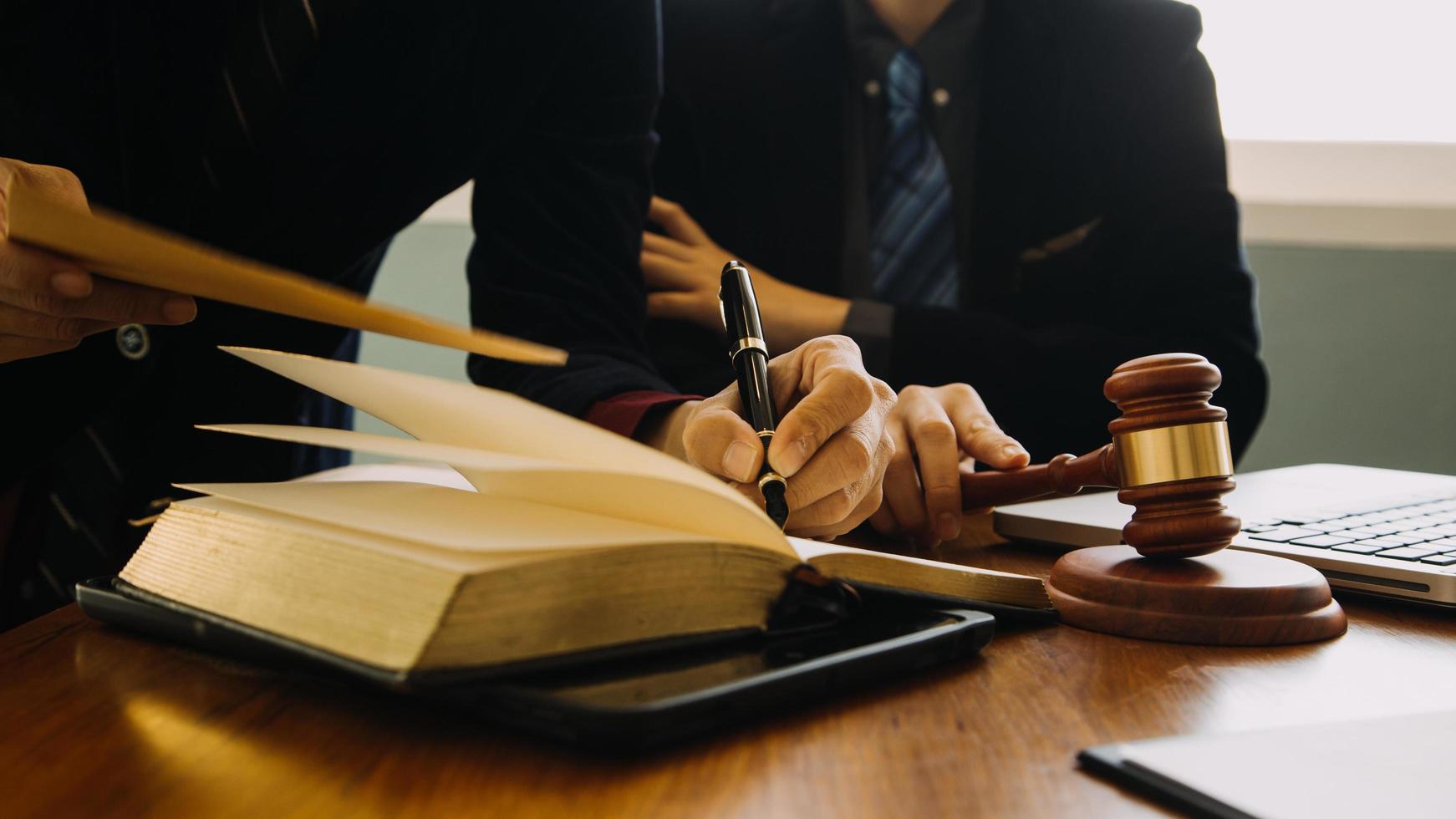 Business and lawyers discussing contract papers with brass scale on desk in office. Law, legal services, advice, justice and law concept picture with film grain effect photo