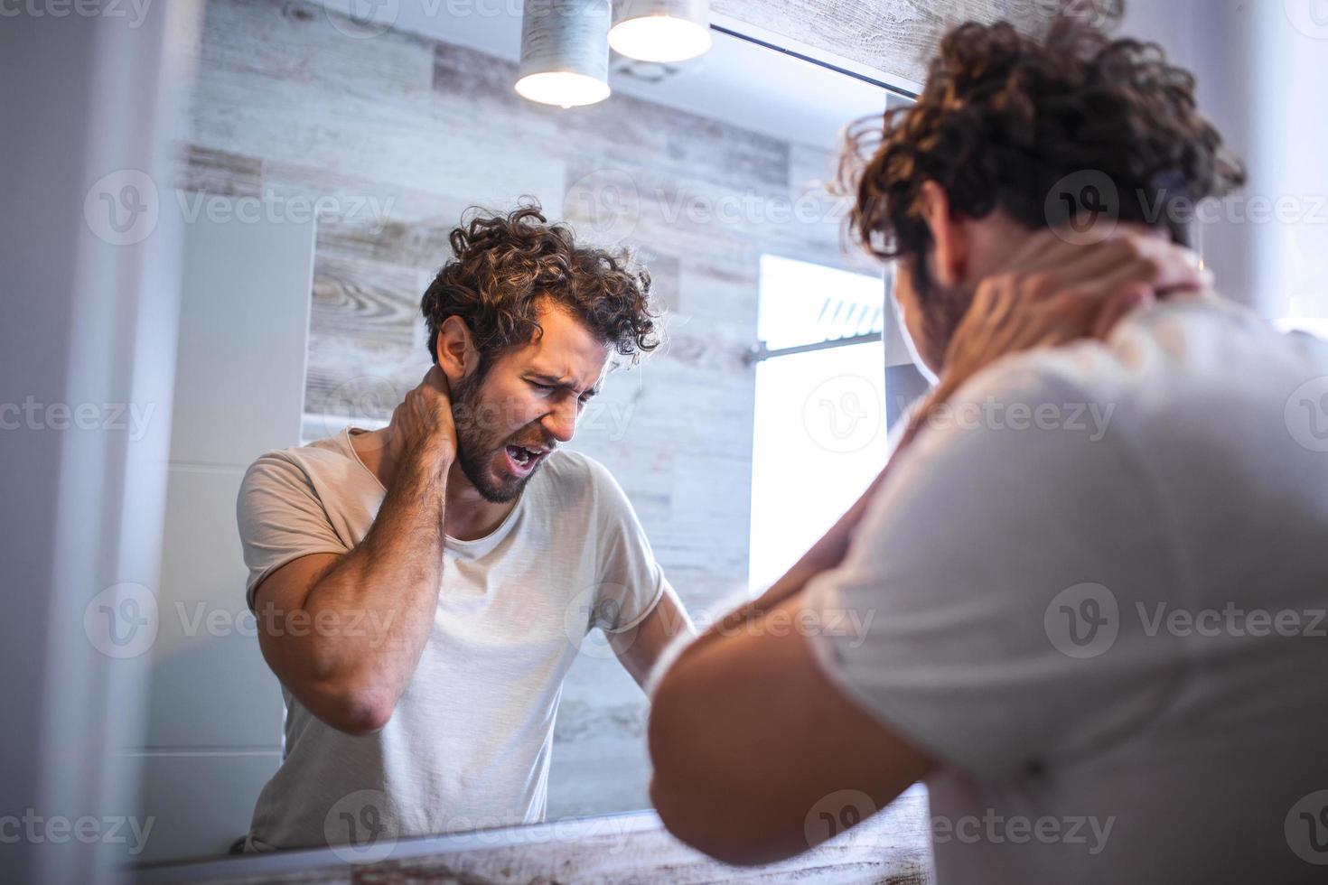 Portrait of sleepy young man yawning and looking at mirror in bathroom in morning, side view. Trying to wake up. Lack of sleep, insomnia and stressful lifestyle. Hangover. depression. photo