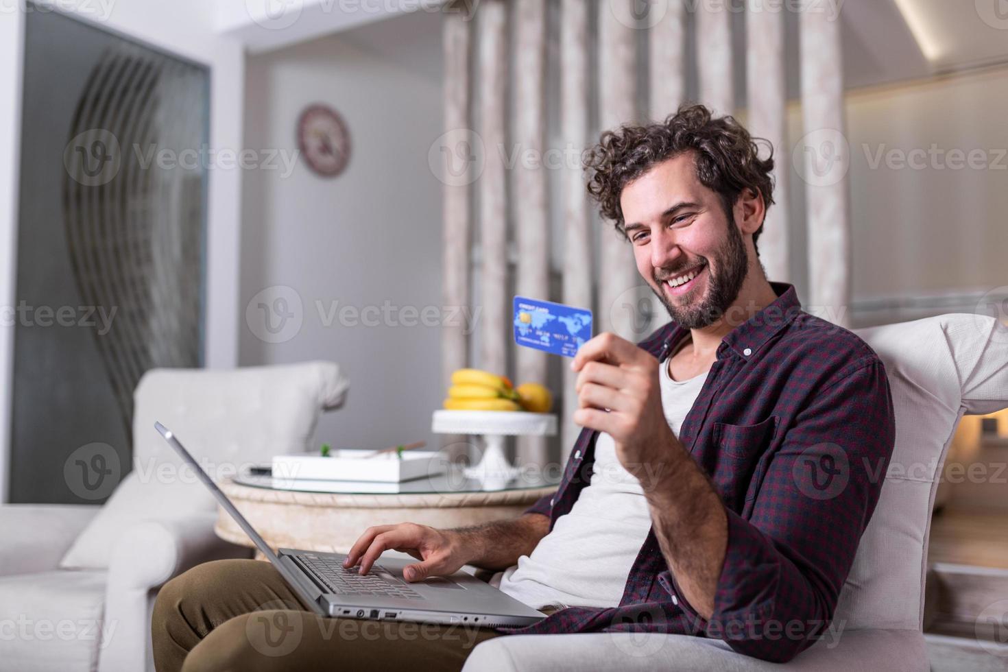 Young Man holding credit card and computer laptop entering data for web-site form, going to pay for online order. People, lifestyle, modern technologies and e-commerce concept photo