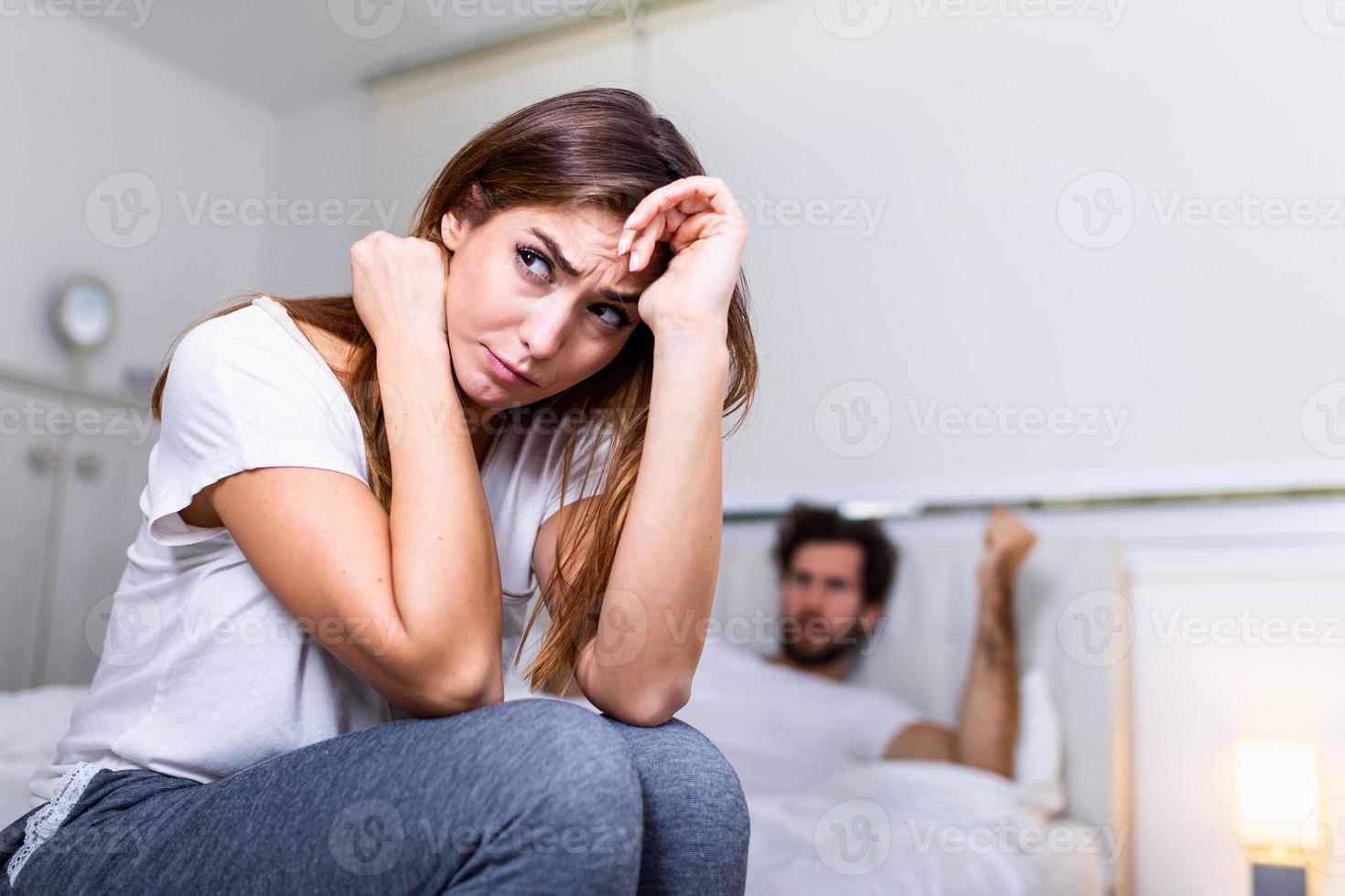 Frustrated sad girlfriend sit on bed think of relationship problems, thoughtful couple after quarrel lost in thoughts, upset lovers consider break up, offended person disappointed by boyfriend photo