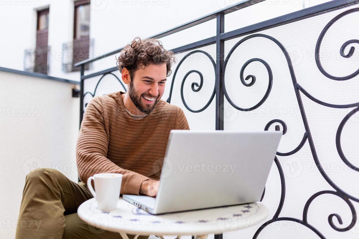 Businessman working on computer, drinking coffee and smiling, business man entrepreneur working on computer, businessman reading emails and holding his mobile phone photo