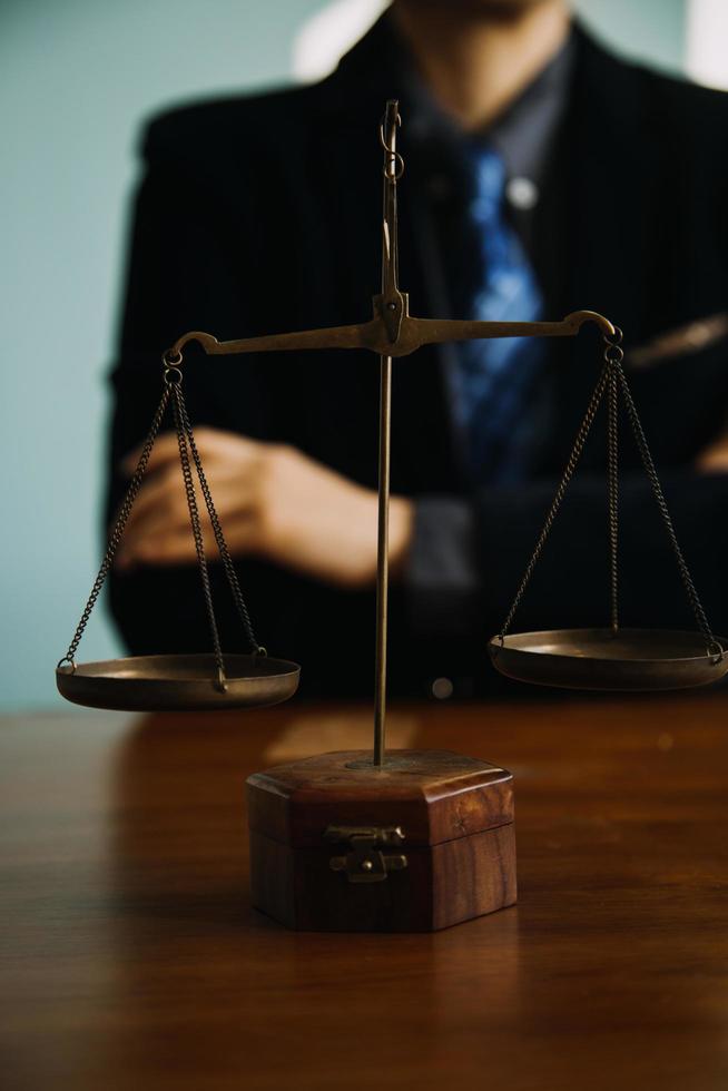 Business and lawyers discussing contract papers with brass scale on desk in office. Law, legal services, advice, justice and law concept picture with film grain effect photo