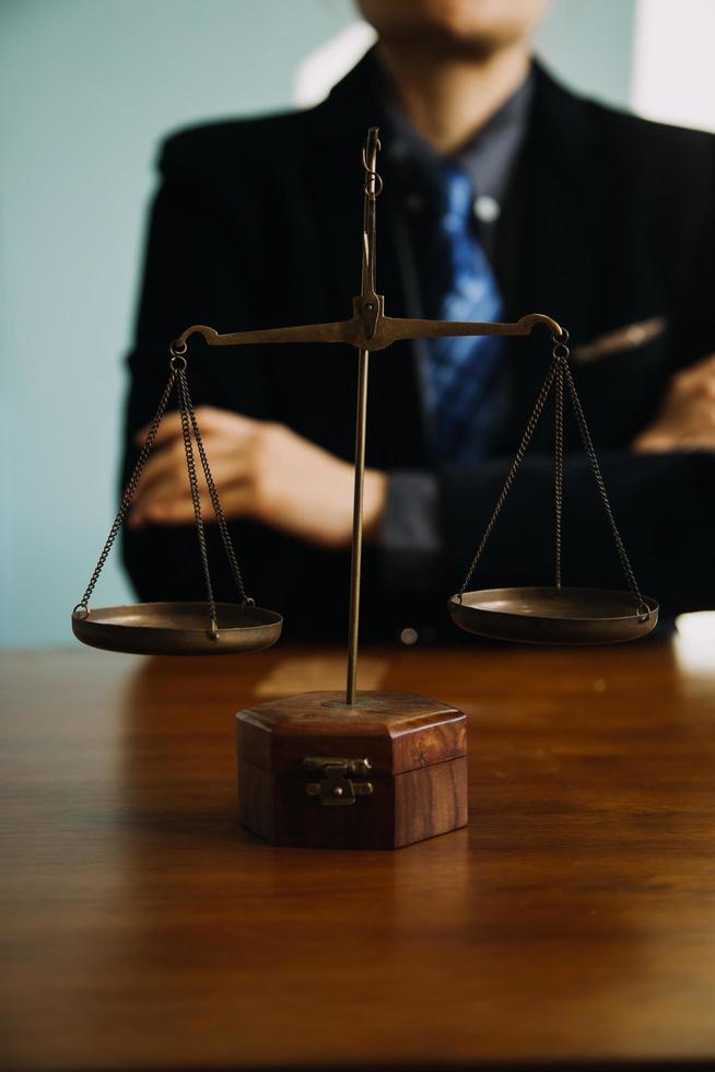 Business and lawyers discussing contract papers with brass scale on desk in office. Law, legal services, advice, justice and law concept picture with film grain effect photo