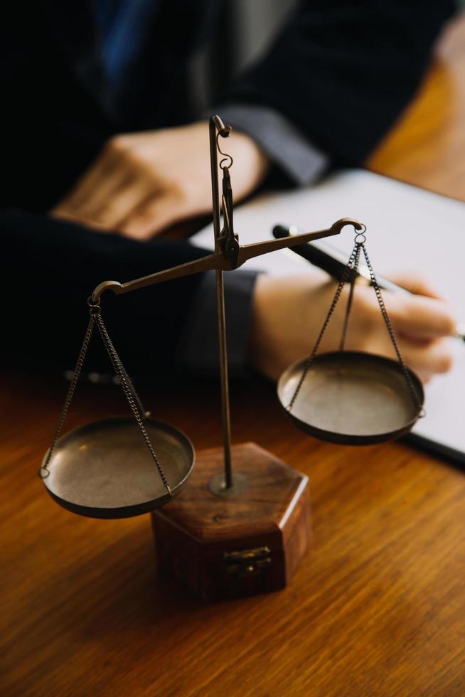 Business and lawyers discussing contract papers with brass scale on desk in office. Law, legal services, advice, justice and law concept picture with film grain effect photo