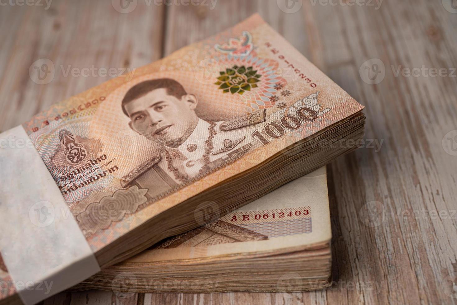 Stack of Thai baht banknotes on wooden background, business saving finance investment concept. photo