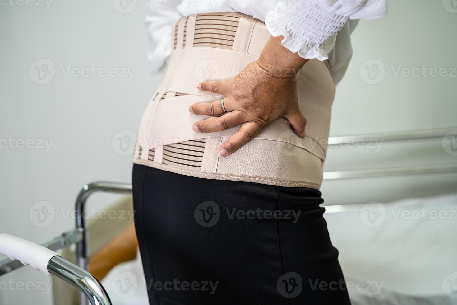 Asian lady patient wearing back pain support belt for orthopedic lumbar with walker. photo