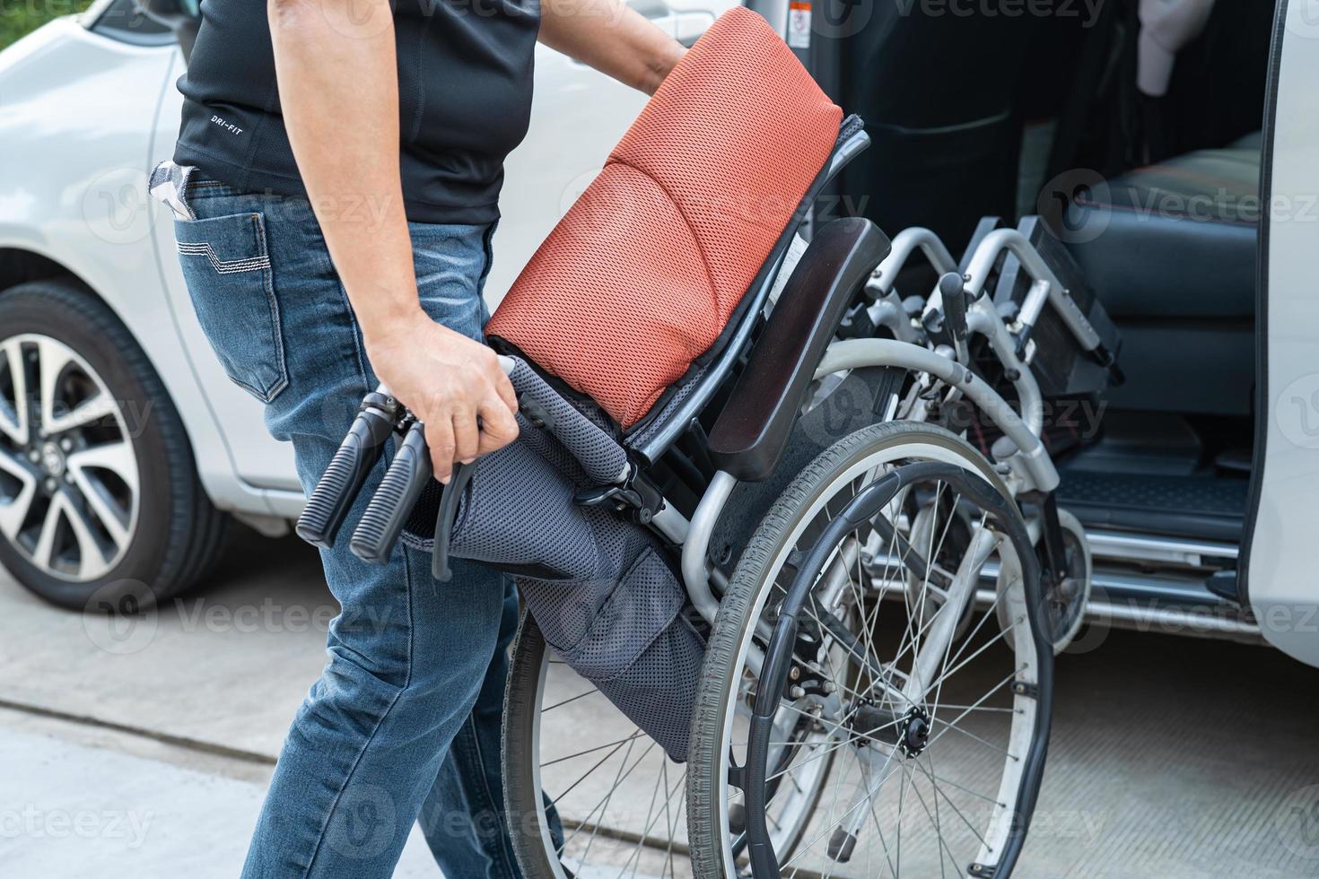 Asian woman folding and lift up wheelchair into her car. Accessibility concept. photo